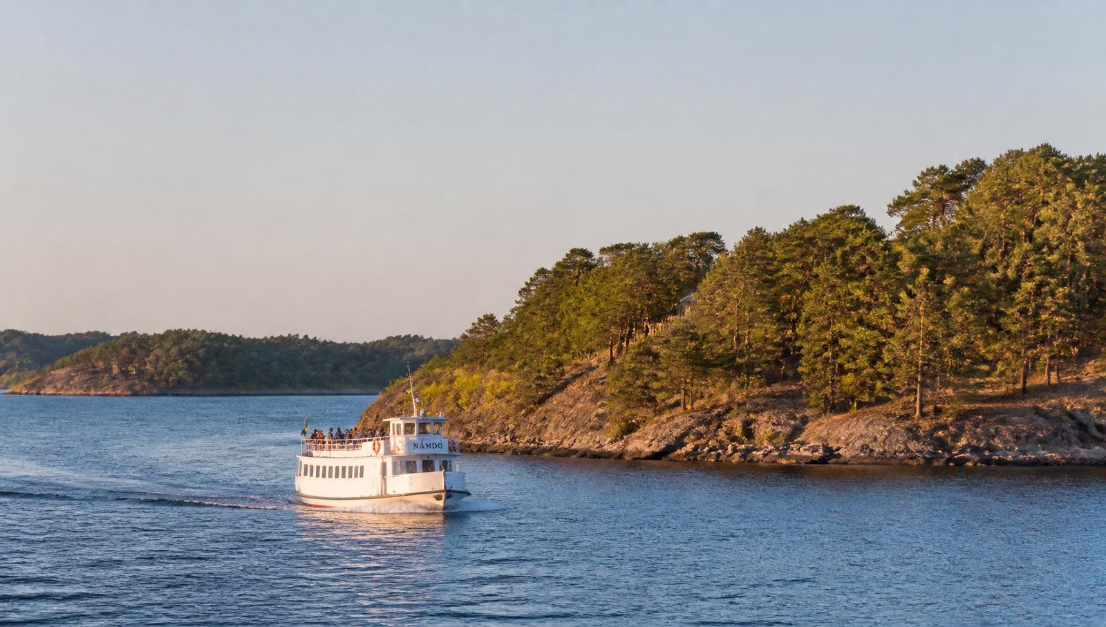 Passagerarbåt på väg mellan skogsklädda öar i svensk skärgård